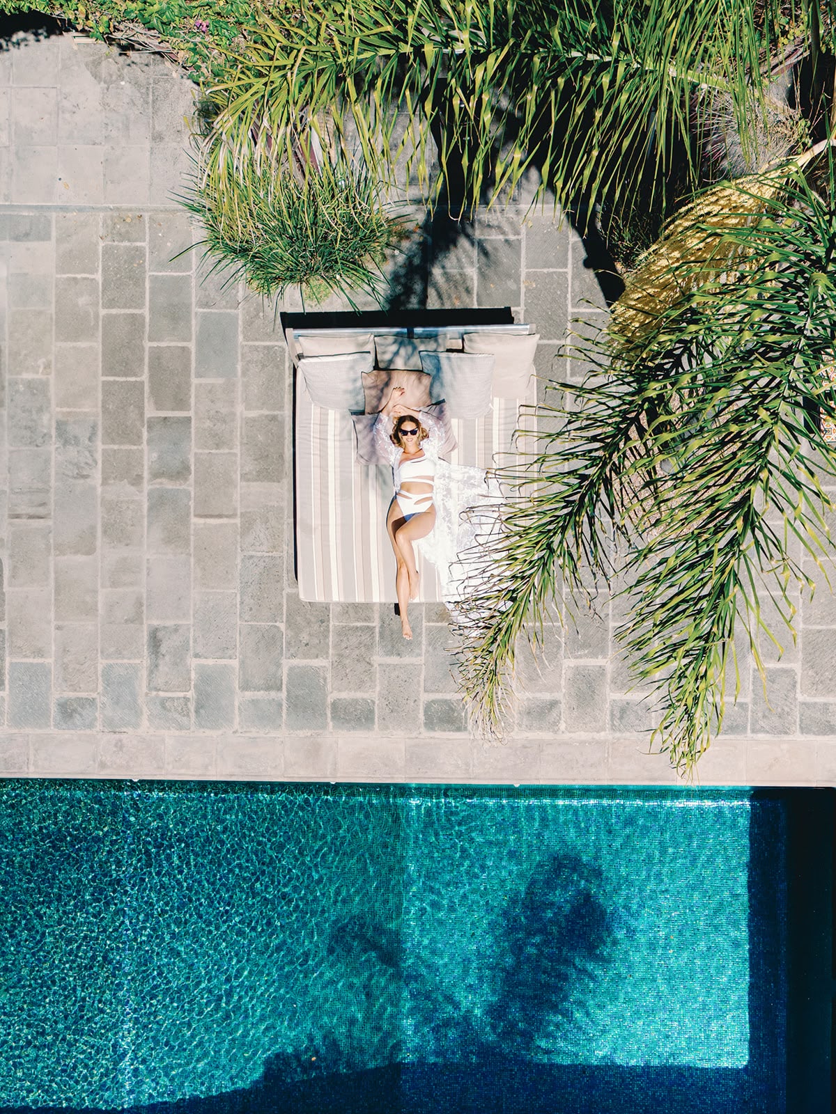 An overhead view of a daybed beside the pool and palms at Hacienda Santa Ana