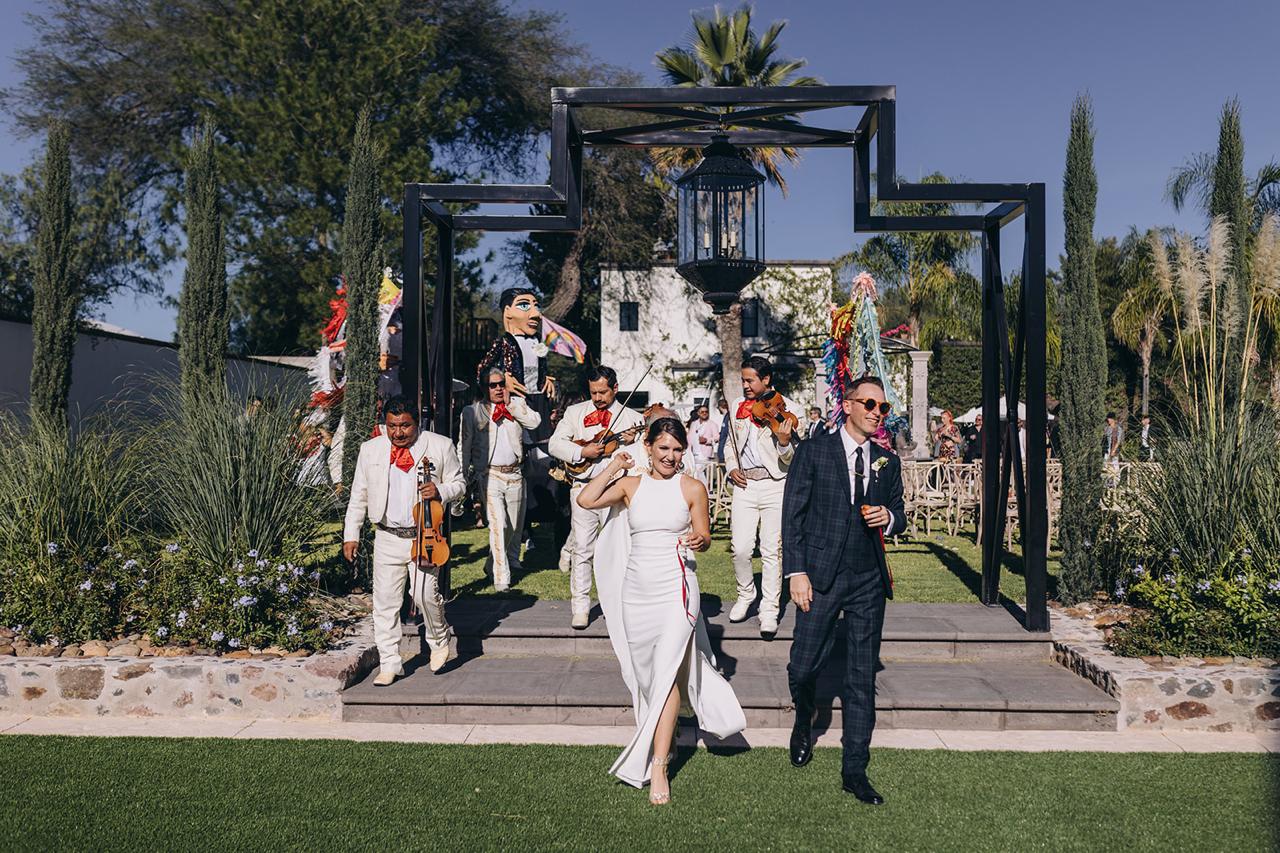 Newlyweds walking through the Event Lawn with mariachi musicians at Hacienda Santa Ana